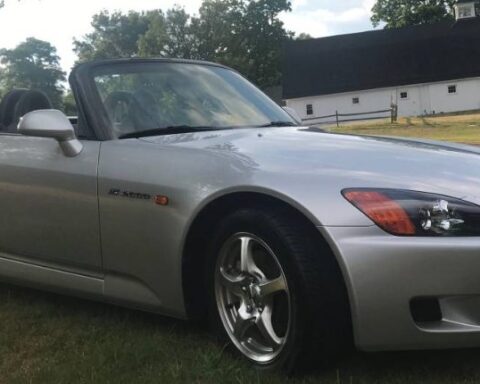 Silver 2002 Honda S2000 roadster with the top down, parked on grass, front three-quarter view