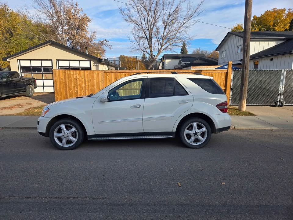 Side profile of the white ML 320 CDI on factory alloy wheels in autumn light