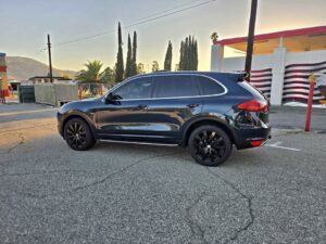 Dark blue 2013 Porsche Cayenne Diesel Platinum Edition on black wheels, side profile in a parking lot