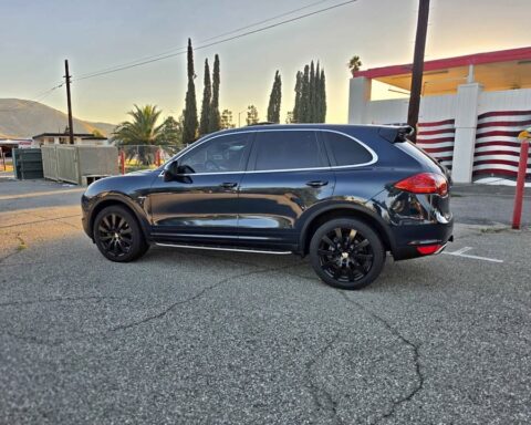 Dark blue 2013 Porsche Cayenne Diesel Platinum Edition on black wheels, side profile in a parking lot