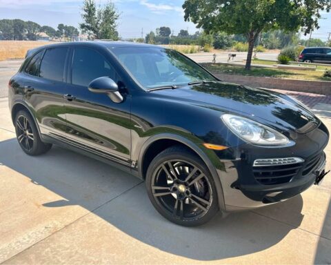 Black 2014 Porsche Cayenne Diesel on black wheels in a driveway, front three-quarter view