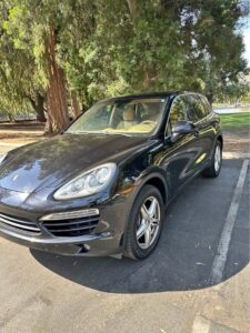 Black 2014 Porsche Cayenne Diesel Platinum Edition parked under trees, front three-quarter view