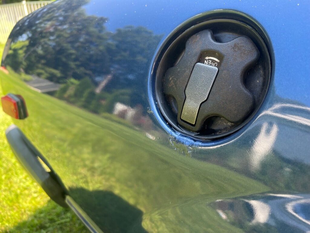 Close-up of the open fuel filler door on the dark blue 280ZX, showing the locking fuel cap