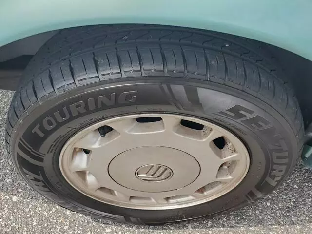 Close-up of the Mercury Sable GS front wheel with a silver Mercury wheel cover and touring tire