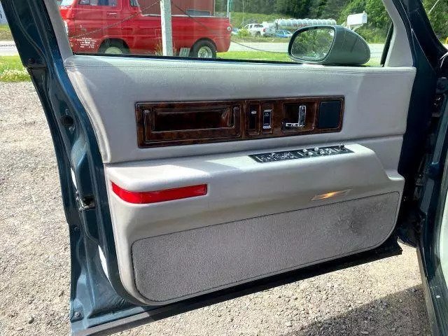 Open driver door of the 1994 Cadillac Fleetwood showing the gray door panel, wood-grain trim and power seat switches