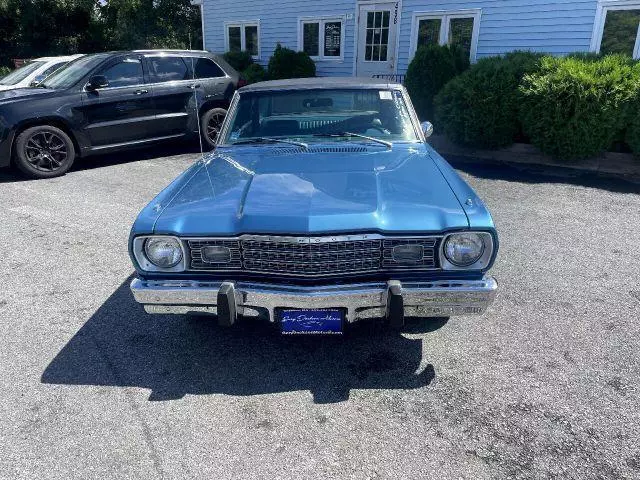 Blue 1974 Plymouth Scamp two-door hardtop on a dealer lot, head-on view showing its grille and bumper guards