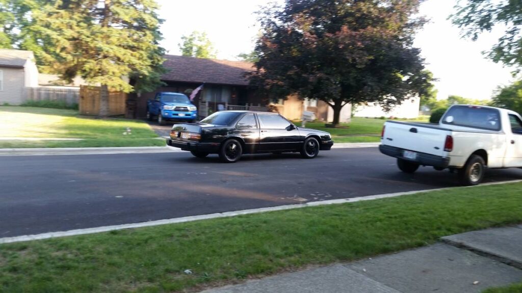 Black 1987 Buick LeSabre T-Type coupe parked on a residential street, rear three-quarter view from a distance