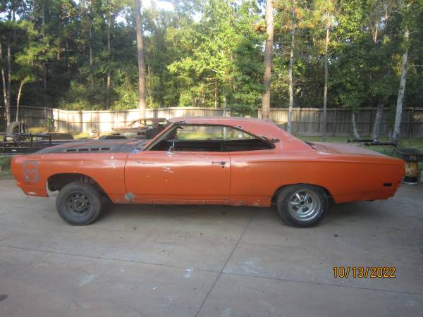 Orange 1969 Plymouth Road Runner hardtop project car, driver-side profile on a concrete driveway with mismatched wheels