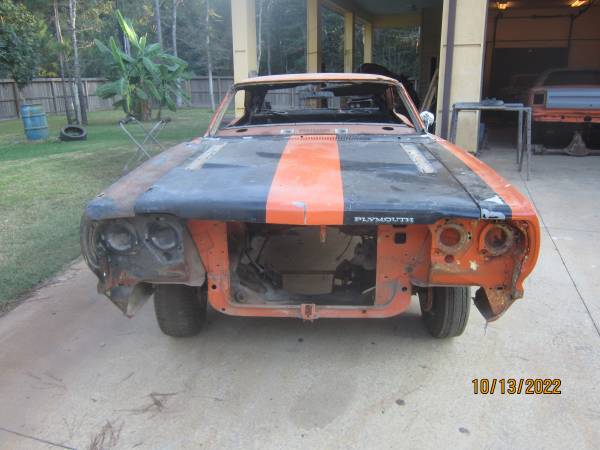 Front of the orange 1969 Plymouth Road Runner with the grille, bumper and headlights removed and a black hood with an orange center stripe