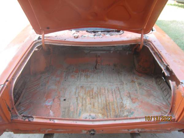 Open trunk of the 1969 Plymouth Road Runner showing a rusted trunk floor and faded orange paint