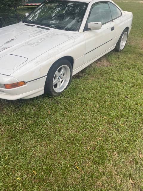 White BMW 850i coupe parked on grass, front three-quarter view with stains on the hood